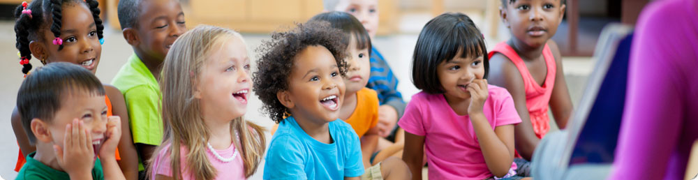 A group of preschool students sitting in a half circle around a teacher.